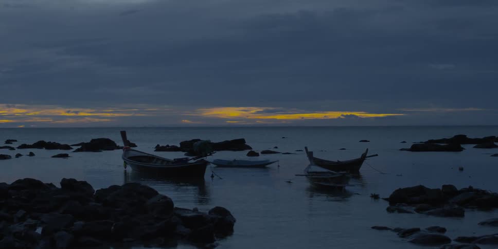 Canoes sitting in a body of water at sunset with many clouds in the sky