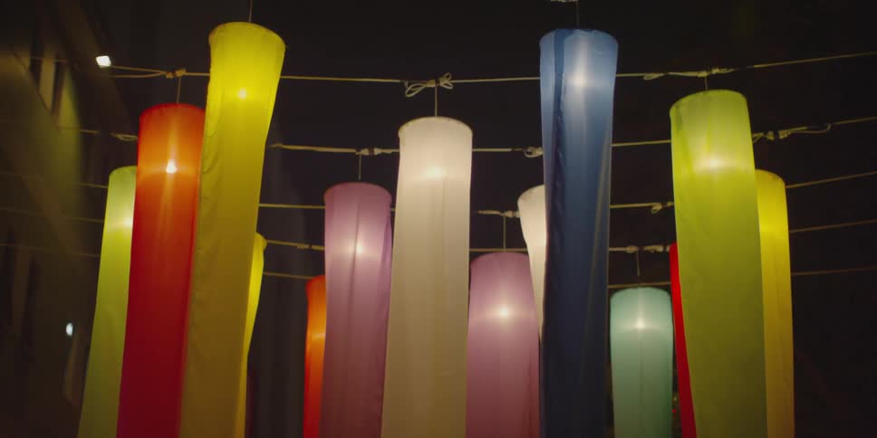 Colorful windsocks with lights hang on lines outside in the dark
