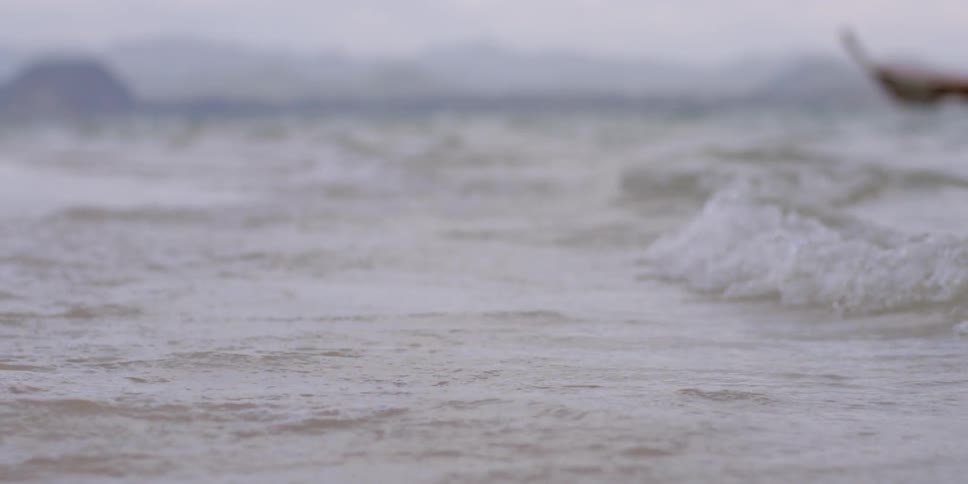 Close up of water waves and a boat floating in the background
