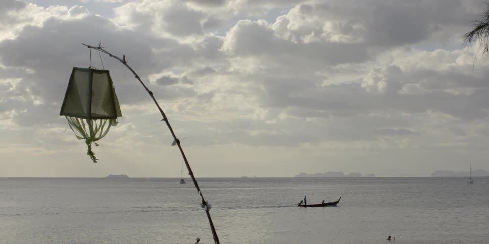 A small boat sails in the water on a cloudy day