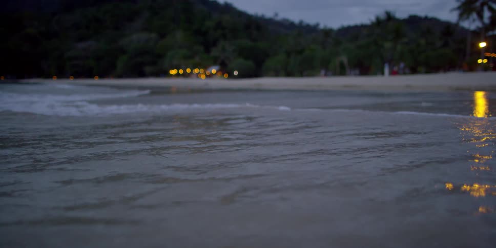Ocean water flowing onto beach at dusk