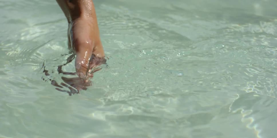Person moving their hand through crystal clear water