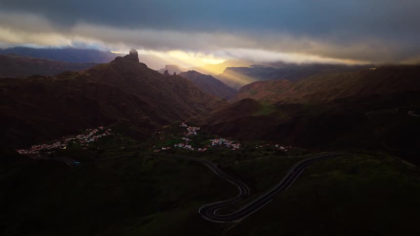 Rural village on a valley next to a road on a mountainous region outdoors during dusk or dawn