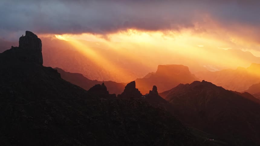 Sunlight shines from a red sky onto foggy mountains