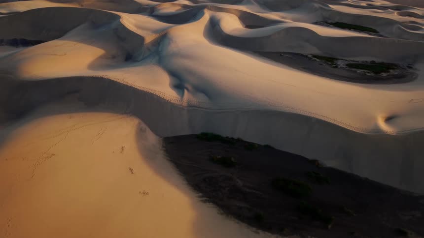 Sunlight shines on desert sand dunes across the landscape