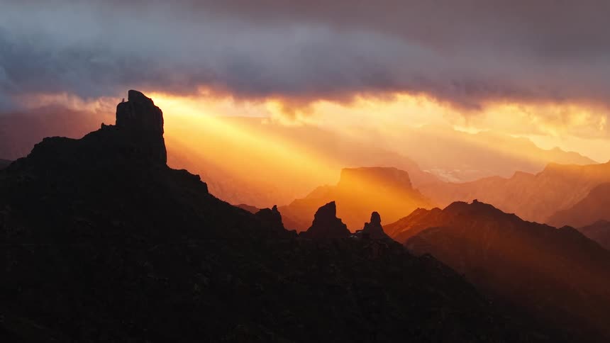 Dark mountains stand out against vibrant sunset sky