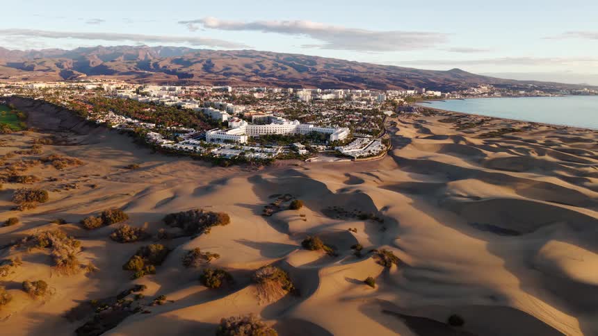 Aerial view of a city surrounded by dunes with the sea in the background