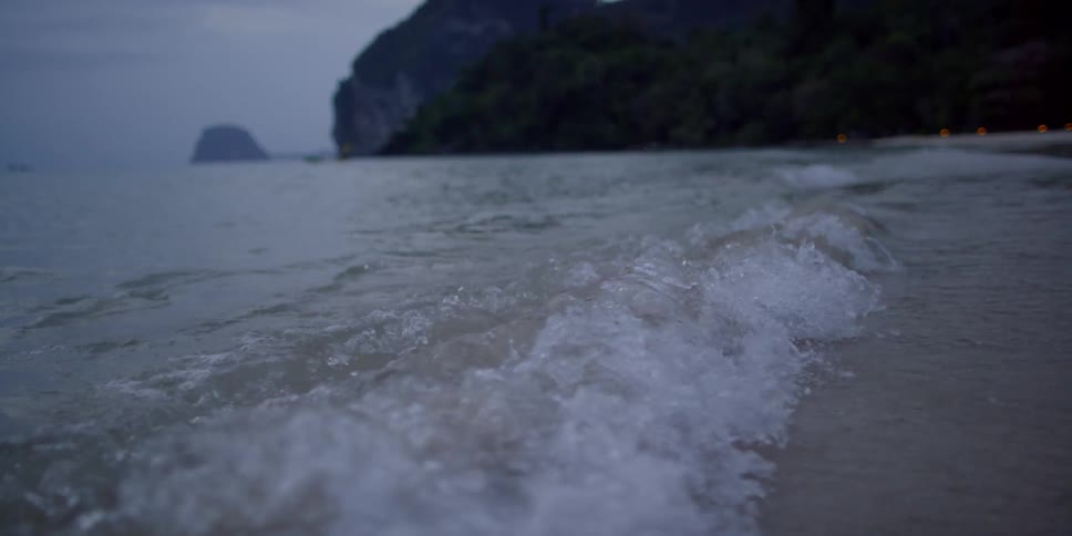 The tide coming in on the beach on a cloudy evening