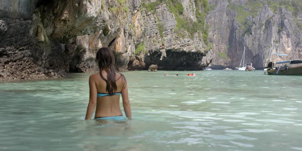 A woman swims in a lake with boats in the distance