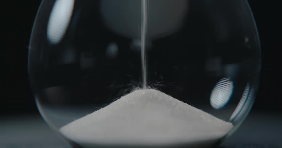 Sand drops to the bottom of an hourglass