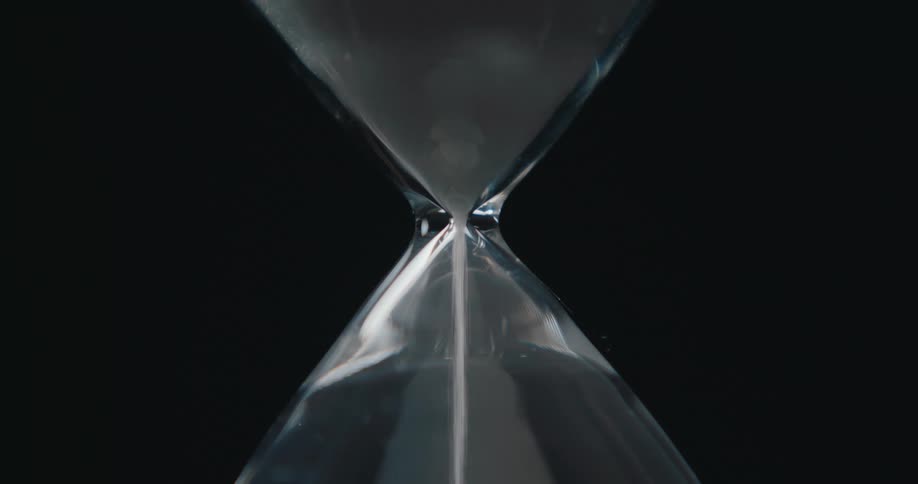 Hourglass with sand falling against a black background