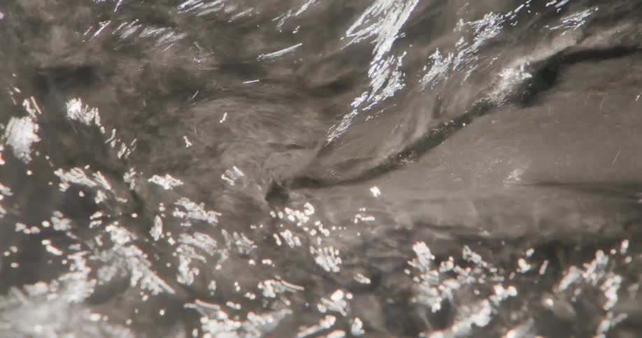 Clear waters flow between rocks in sunlit stream