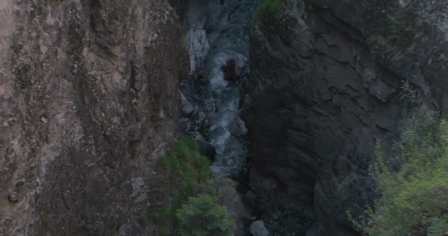 A stream flows down a rocky mountain at midday