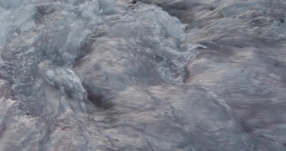 Turbulent water flows over a rocky surface in continuous motion