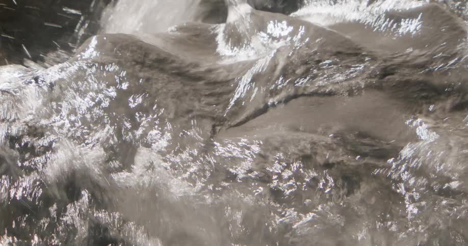 Clear water flowing over smooth rock with shimmering reflections