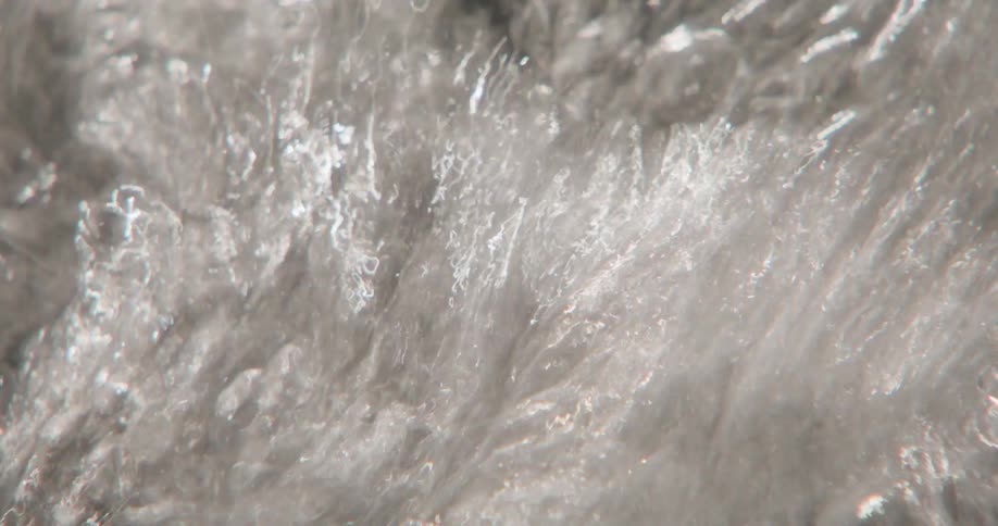 Flowing water moves rapidly over rocks in a riverbed