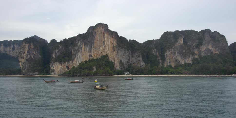 People in canoes on body of water next to large rock mountains