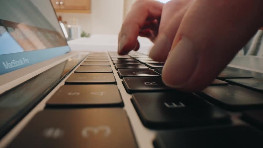 Fingers press macbook pro keys in indoor setting