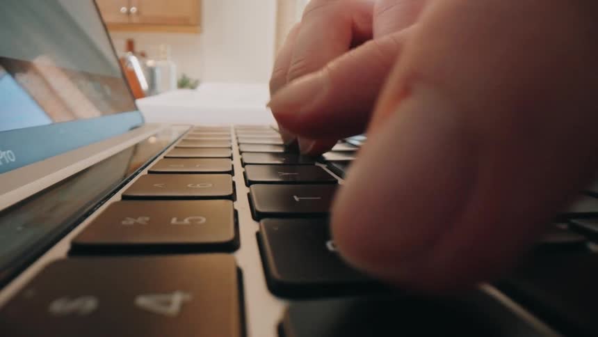 Young womans fingers typing on the keyboard of a laptop computer