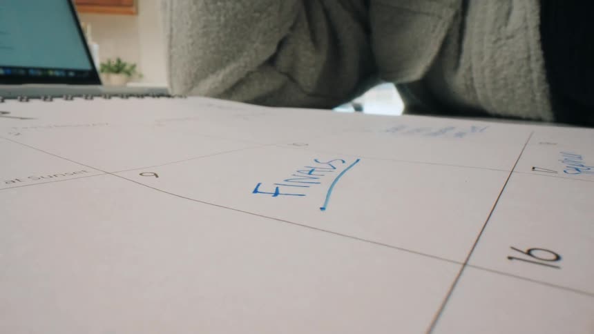 Hand with a pen writing on a calendar