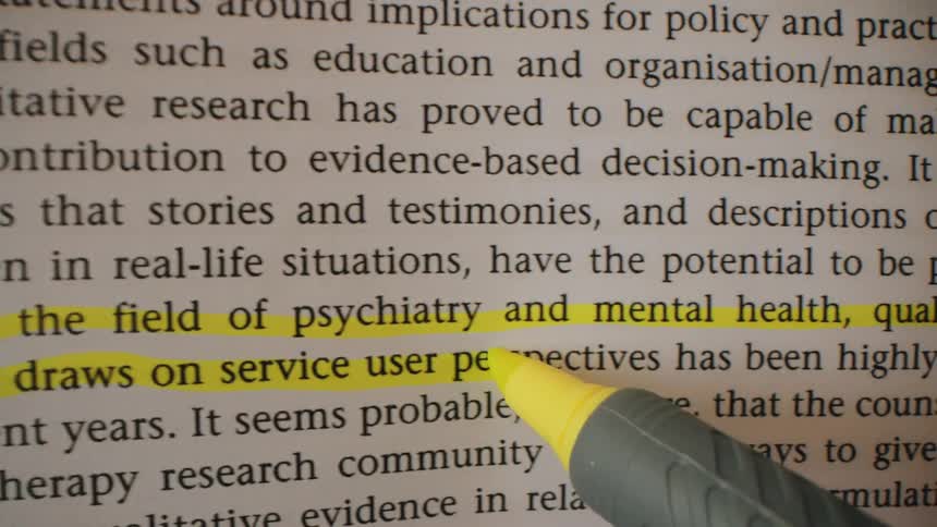 A yellow highlighter moves across a page emphasizing text about qualitative research in the field of psychiatry and mental health the closeup shot focuses on the tip of the marker as it smoothly glides over the printed words