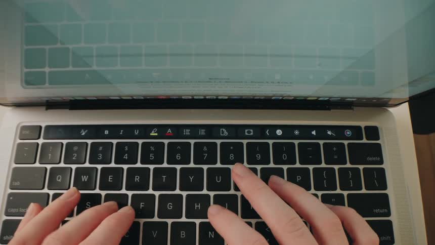 Closeup of a hand typing on a laptop keyboard in an office
