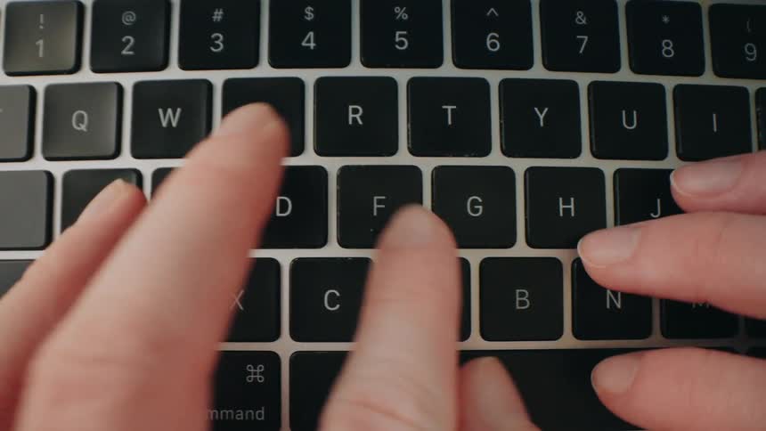 A persons hands typing on a laptop