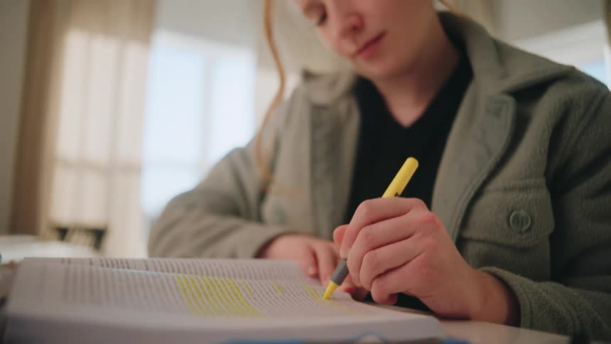 Woman making notes with a highlighter in a book