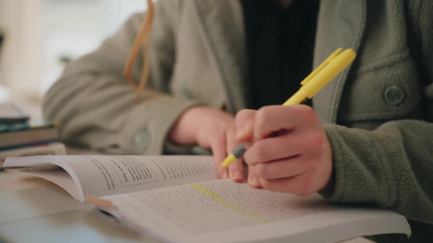 Teenage girl using a marker to highlight text in her book