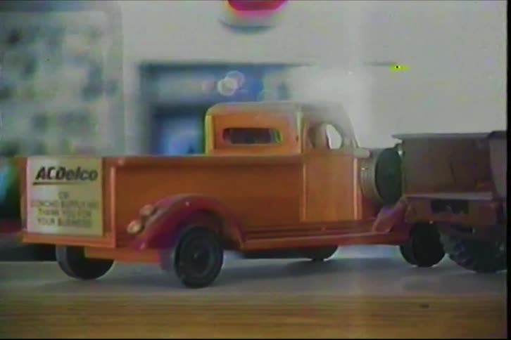 Orange model pickup truck displays acdelco logo on wooden surface