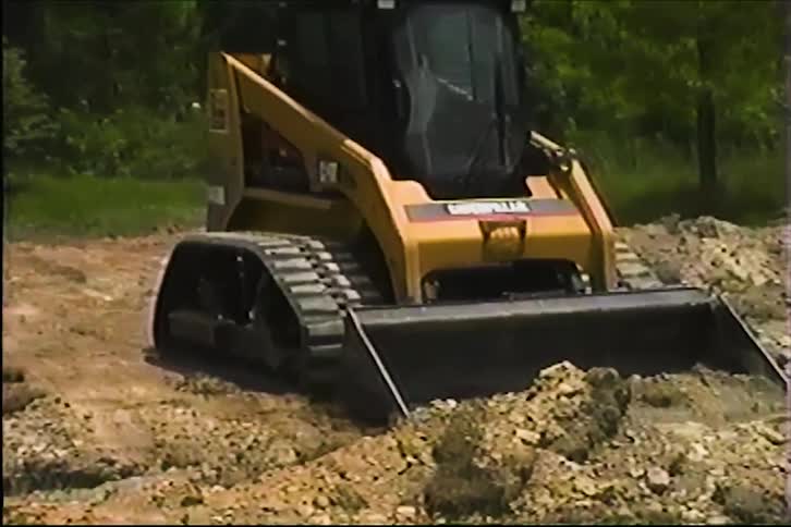 The video features a yellow caterpillar compact track loader working on a construction site or plot of land