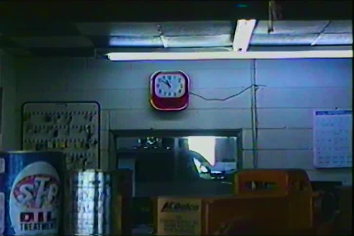 Red clock showing 910 in workshop with automotive products and tools on the wall