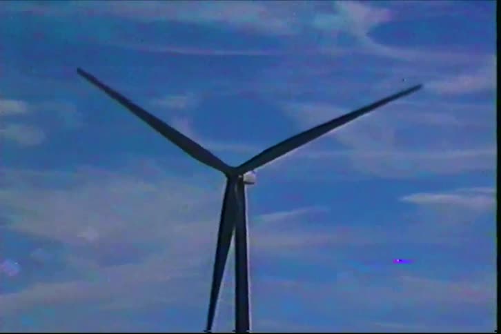 A windmill in a wind farm at midday its blades spinning nonstop