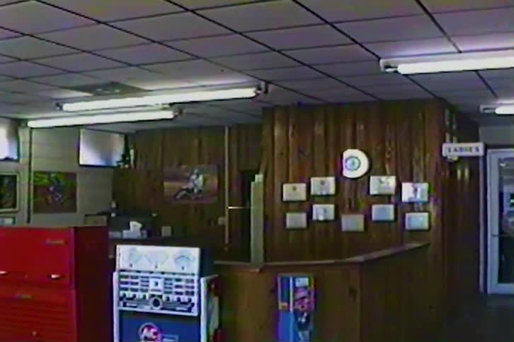 The empty wood paneled waiting area of a vintage auto repair shop is shown