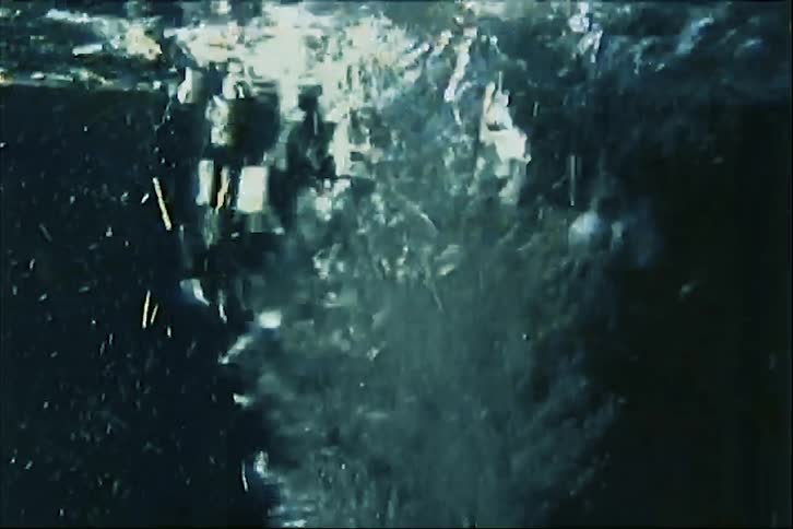 Moving water surface shows bubbles and reflections under low light