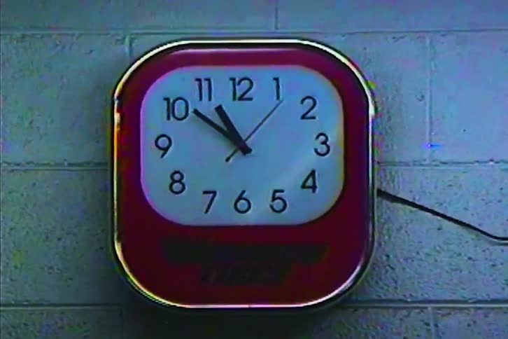 Red and white wall clock shows approximately 1010 against a block wall background