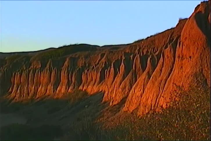Eroded rock formations illuminated by lowangle light along an arid slope