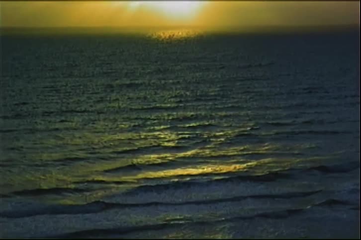 Ocean waves calm with the sun on the horizon