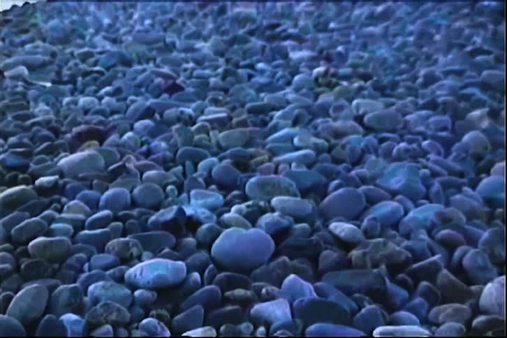 A series of small rocks and pebbles scattered out in the open at midday