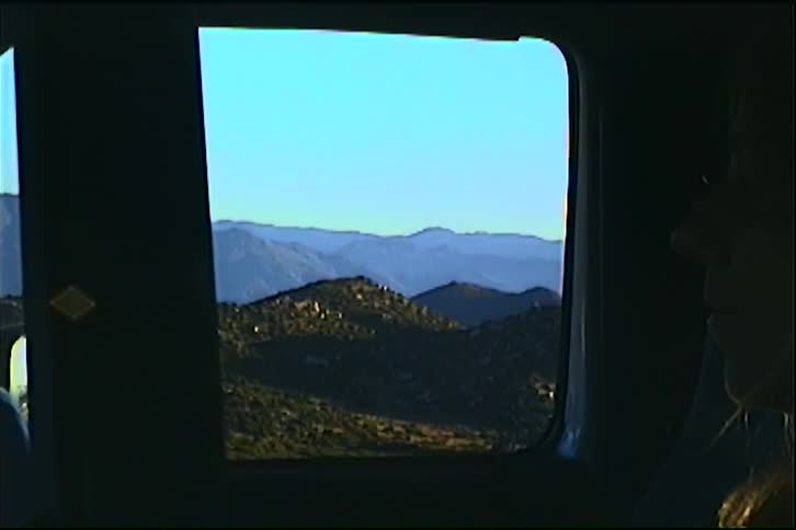 Woman gazes at mountain landscape through vehicle window