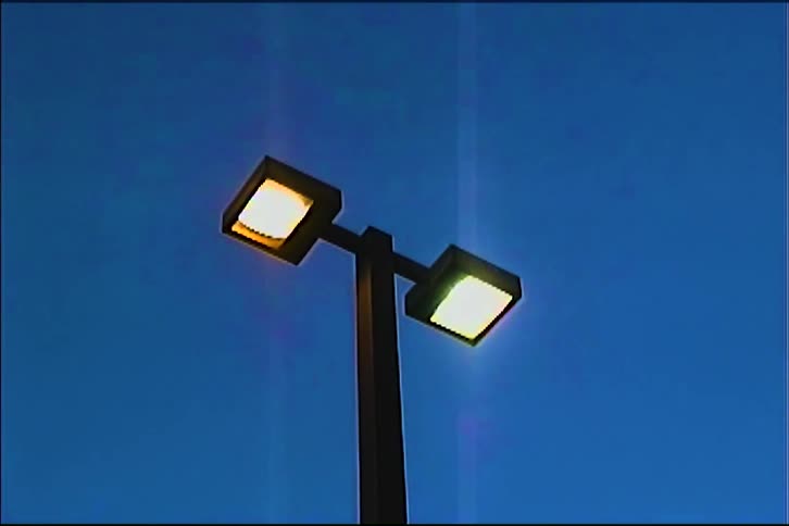 Street light lit against the blue night sky