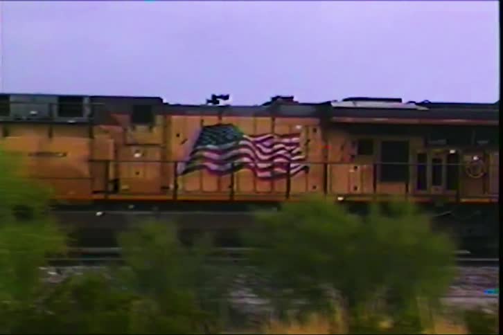 Yellow union pacific locomotive rolls down tracks under cloudy sky in rural landscape
