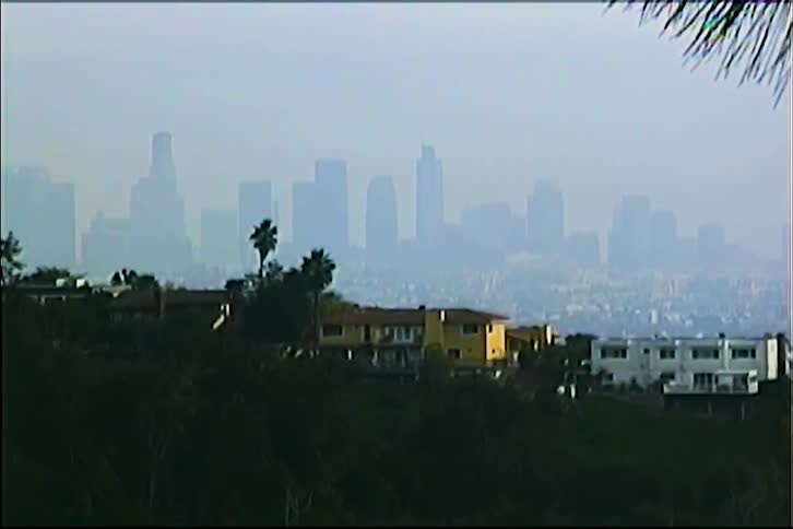 Large houses stand on a hill overlooking a fog obscured city