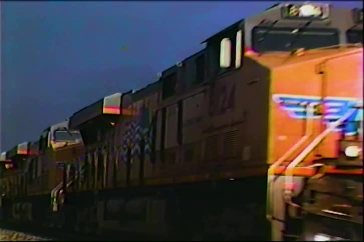 Brown locomotive moving along the tracks on a cloudy day
