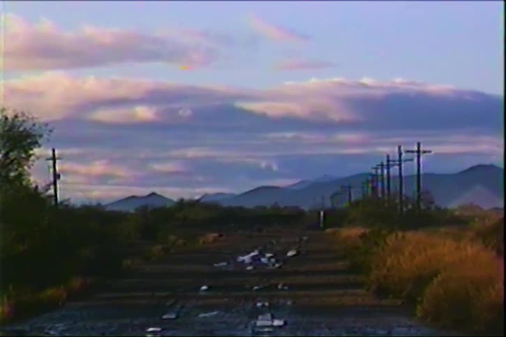 A quiet countryside road stretches into the distance lined with utility poles along the side as they follow the curve of the landscape under the open sky