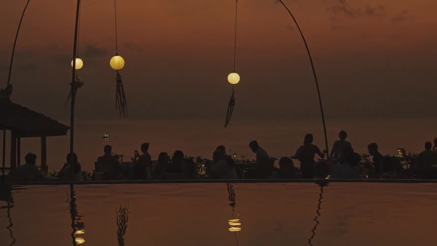 People dine outside at a restaurant by the water
