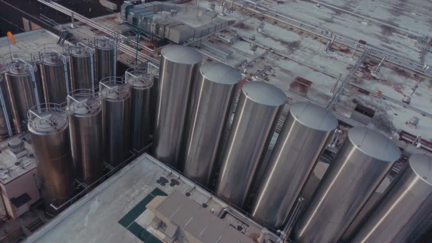 Aerial of cylindrical metal structures at a production factory during daytime