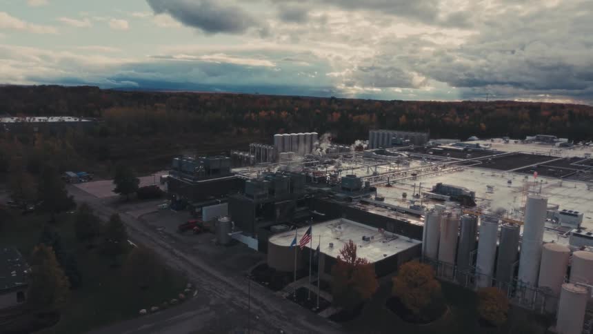 Aerial view of an industrial factory complex with autumn trees around under a cloudy sky