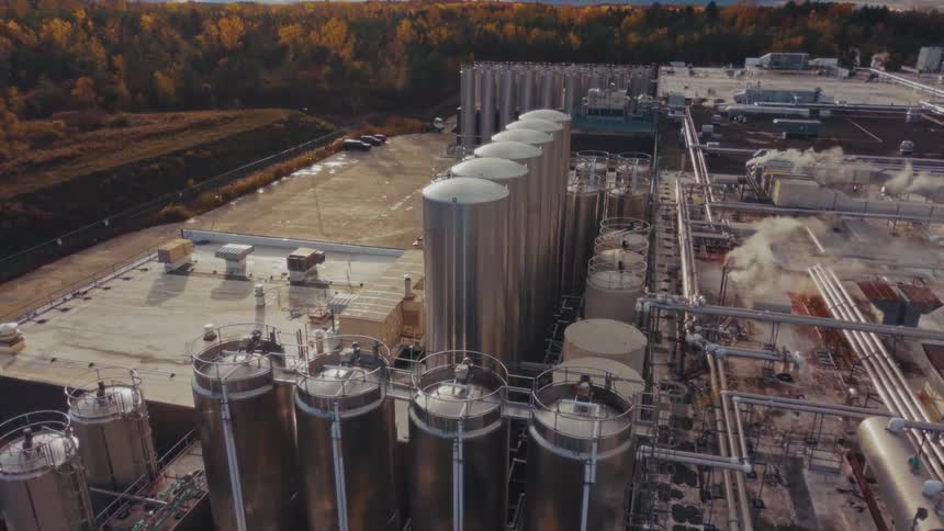 Aerial view of a factory with pipelines surrounded by a forest