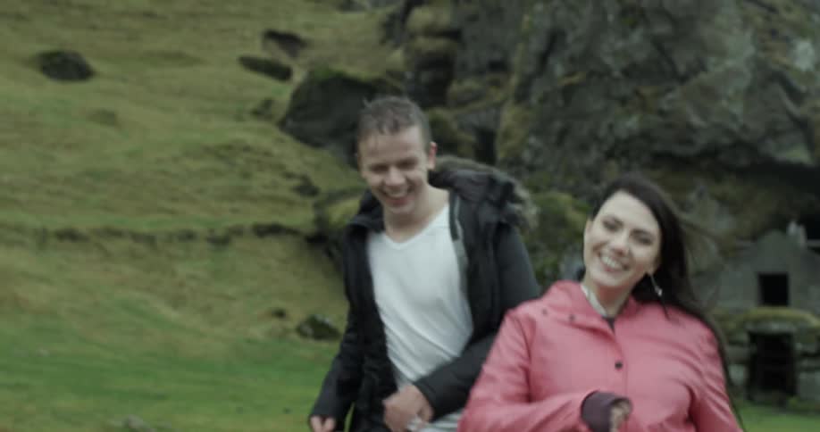 Man and woman laughing and running in a field